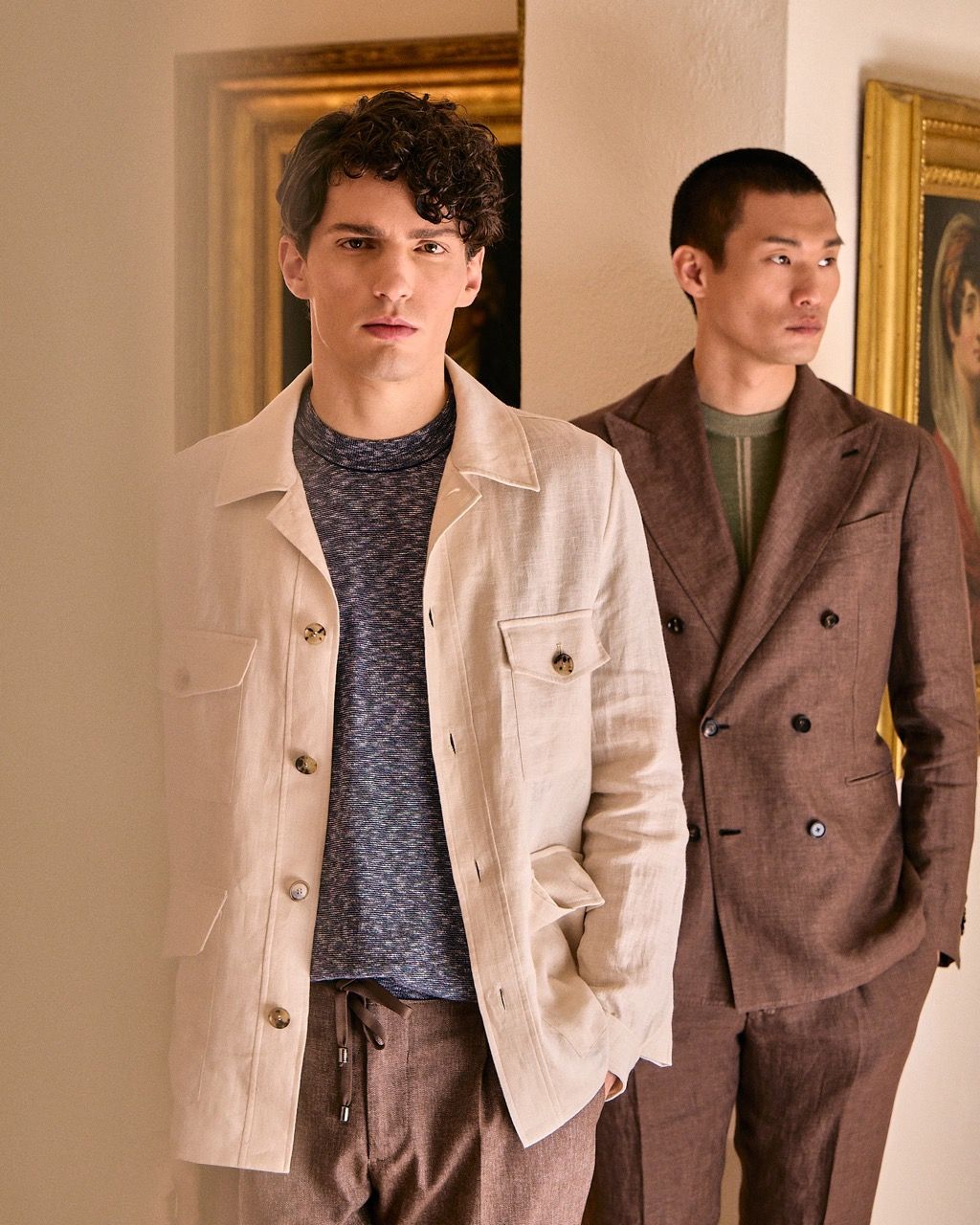two men side-by-side posing in semi-formal wear, with golden frames behind them
